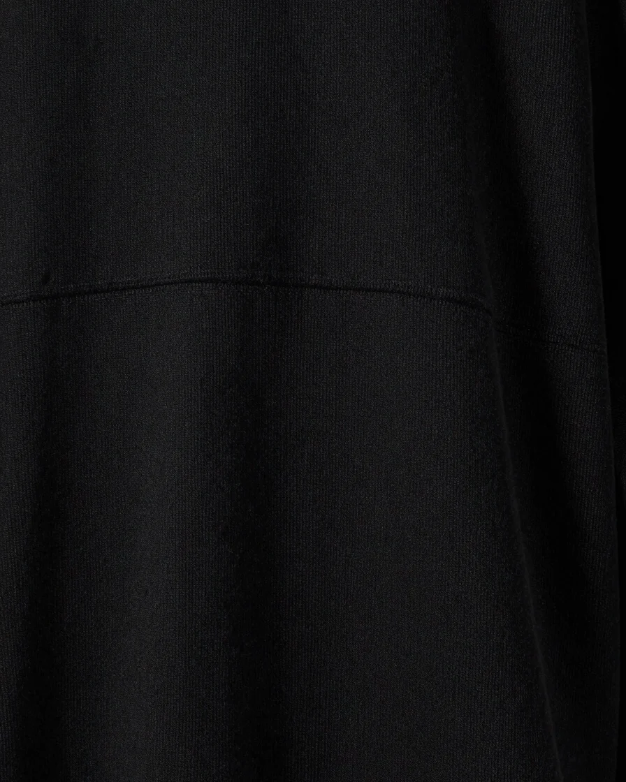 Detail close-up of heavyweight black cotton fabric texture, clean woven seams, and minimal tonal embroidery in a bright